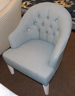 Lot 495 - A modern armchair covered in blue buttoned fabric, with white painted legs, 68cm wide