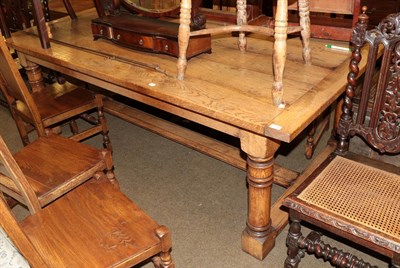 Lot 515 - A reproduction oak dining table raised on gun barrel legs with block feet, 218cm long