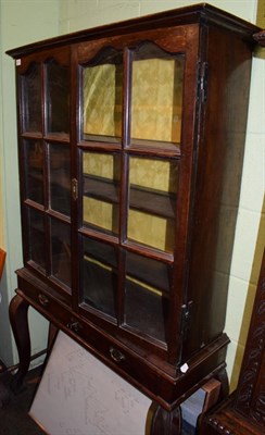 Lot 558 - An oak glazed cabinet on stand, with two doors enclosing adjustable shelves, raised on a stand with