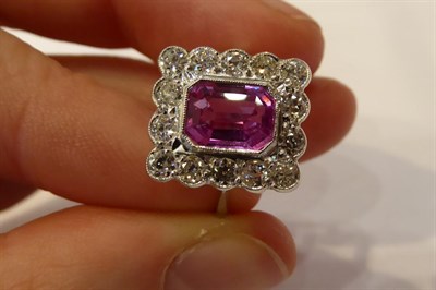 Lot 3267 - A Pink Sapphire and Diamond Cluster Ring, the emerald-cut pink sapphire within a border of...