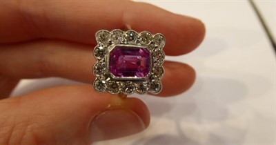 Lot 3267 - A Pink Sapphire and Diamond Cluster Ring, the emerald-cut pink sapphire within a border of...