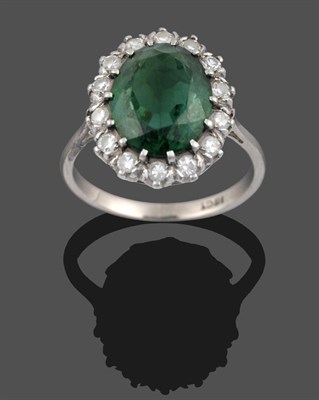 Lot 3269 - A Green Tourmaline and Diamond Cluster Ring, the oval cut green tourmaline within a border of round