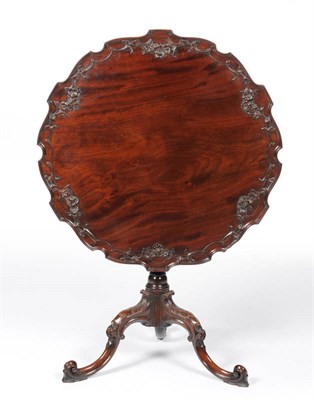 Lot 1305 - A George II Style Mahogany Tripod Table, the scalloped and carved flip-top above a fluted part...