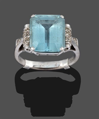 Lot 3352 - An Aquamarine and Diamond Ring, the central emerald-cut aquamarine in a white claw setting, flanked
