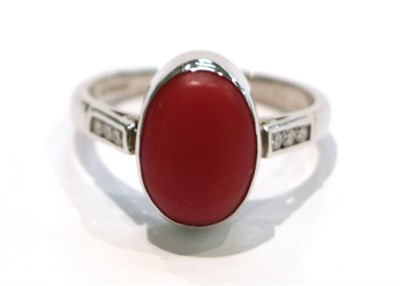 Lot 248 - An 18 carat white gold coral and diamond ring, the oval cabochon coral in a white collet setting to