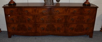 Lot 1195 - A walnut and feather banded sideboard with an arrangement of drawers, 241cm wide