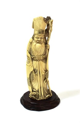 Lot 1099 - A Chinese Ivory Figure of a Sage, 19th century, the bearded figure wearing a tall hat and...