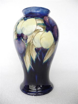 Lot 1401 - A William Moorcroft "Wisteria" Baluster Vase, on a blue ground, impressed factory mark and...