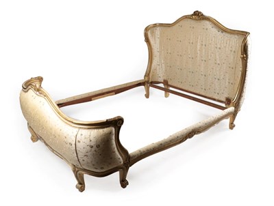 Lot 1494 - A French Louis XV Style Carved Giltwood Bedstead, late 19th century, recovered in floral gilt...