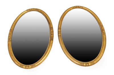 Lot 1557 - A Pair of Victorian Gilt Gesso Oval Wall Mirrors, 3rd quarter 19th century, the bevelled glass...