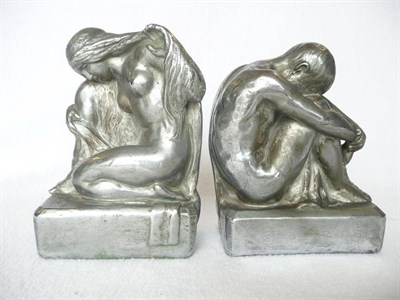 Lot 1491 - A Pair of White Metal Figural Bookends, modelled as a nude kneeling female and a semi-nude...