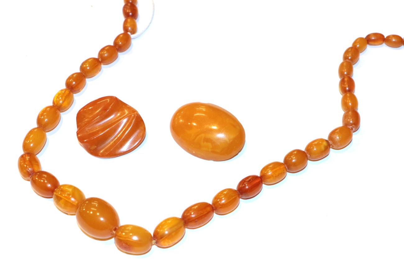 Lot 238 - An amber type necklace, length 64cm; and two amber brooches