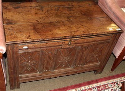 Lot 555 - An early 18th century oak coffer, with three carved panels, raised on stile feet