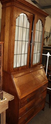 Lot 570 - A 1920s oak bureau bookcase with leaded glass doors, 92cm wide