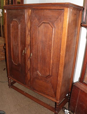 Lot 582 - A late 19th/early 20th century oak two door cupboard, raised on bobbin turned legs and bun feet