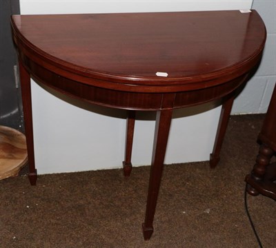 Lot 583 - A Georgian style mahogany demi-lune fold over card table, on tapered legs and spade feet