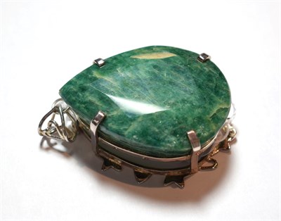 Lot 14 - An emerald pendant, the pear cut emerald in a white claw setting to a scroll border, measures 7.9cm