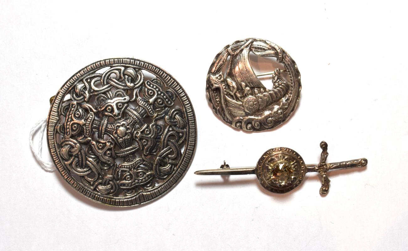 Lot 174 - Two Scottish silver brooches including a gem set example; and a circular mask decorated brooch,...