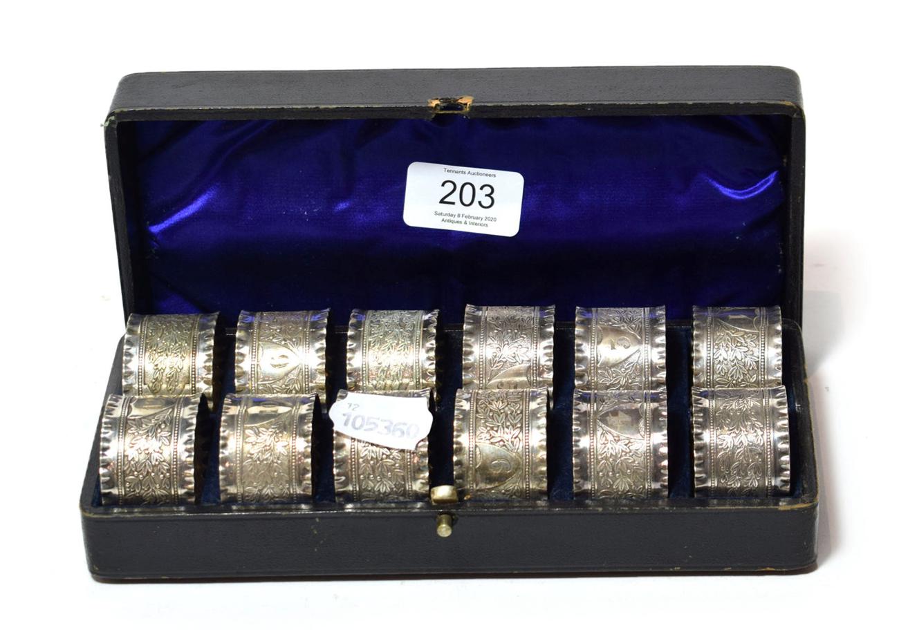 Lot 203 - A cased set of twelve Victorian silver plated napkin rings, each with crimped rims and engraved...