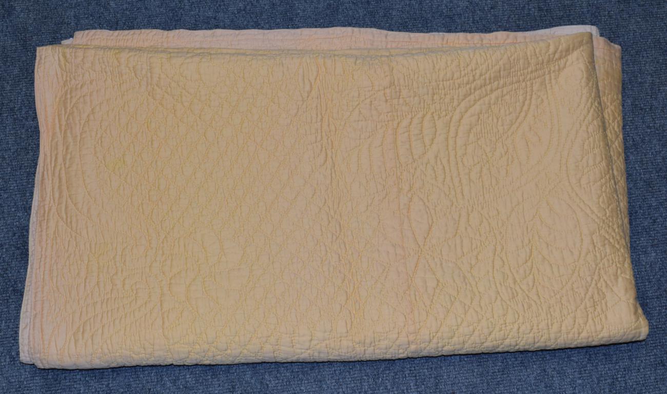 Lot 1045 - Large early 20th century reversible whole cloth quilt, in pale apricot cotton and pale yellow...