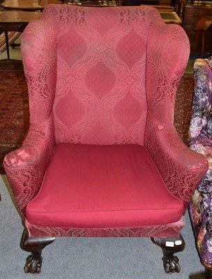 Lot 1208 - A Victorian wingback chair covered in red fabric, raised on claw and ball feet, with later...