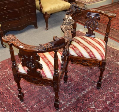 Lot 1233 - A reproduction carved mahogany conversation sofa, decorated with masks and scrolling leaves