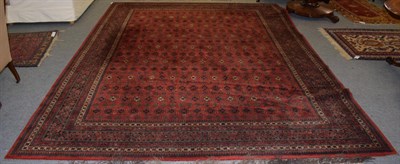 Lot 1266 - A machine made carpet of Turkmen design, the crimson field with columns of guls enclosed by stepped