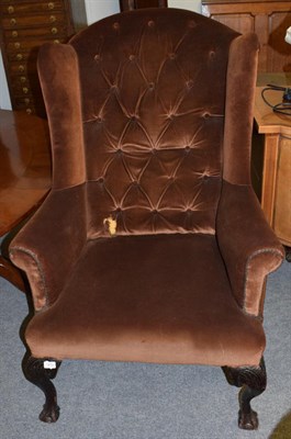 Lot 1272 - A 1930s Georgian style wing armchair raised on ball and claw feet