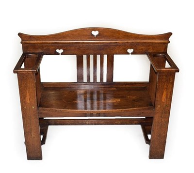 Lot 1182 - An Arts & Crafts Oak and Stencilled Hall Bench, the shaped back with pierced heart motifs, the...