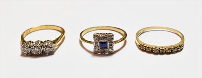 Lot 63 - A diamond three stone ring, stamped '18CT', finger size N; a sapphire and diamond cluster ring,...