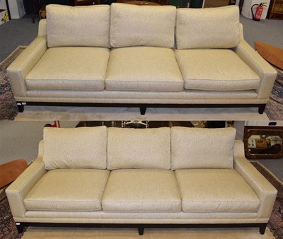 Lot 1086 - A pair of modern three seater sofas upholstered in a shimmering gold effect fabric with square form