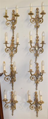 Lot 1095 - A set of eight gilt metal twin-light figural wall sconces, decorated with musical putto
