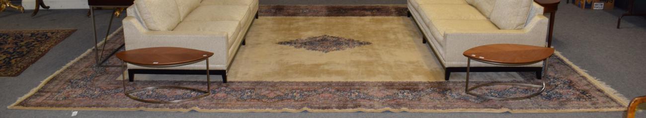 Lot 1125 - Kirman carpet, the plain champagne field centred by an indigo floral diamond medallion, enclosed by