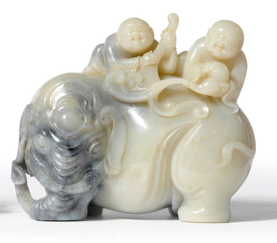 Lot 247 - A Chinese Mutton Fat Jade Type Carving of Two Smiling Boys on the Back of an Elephant, 20th...