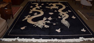 Lot 1137 - A large dragon design rug, the jet black field with two fighting dragons chasing a flaming...