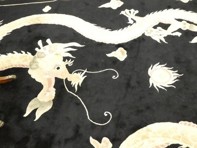 Lot 1137 - A large dragon design rug, the jet black field with two fighting dragons chasing a flaming...