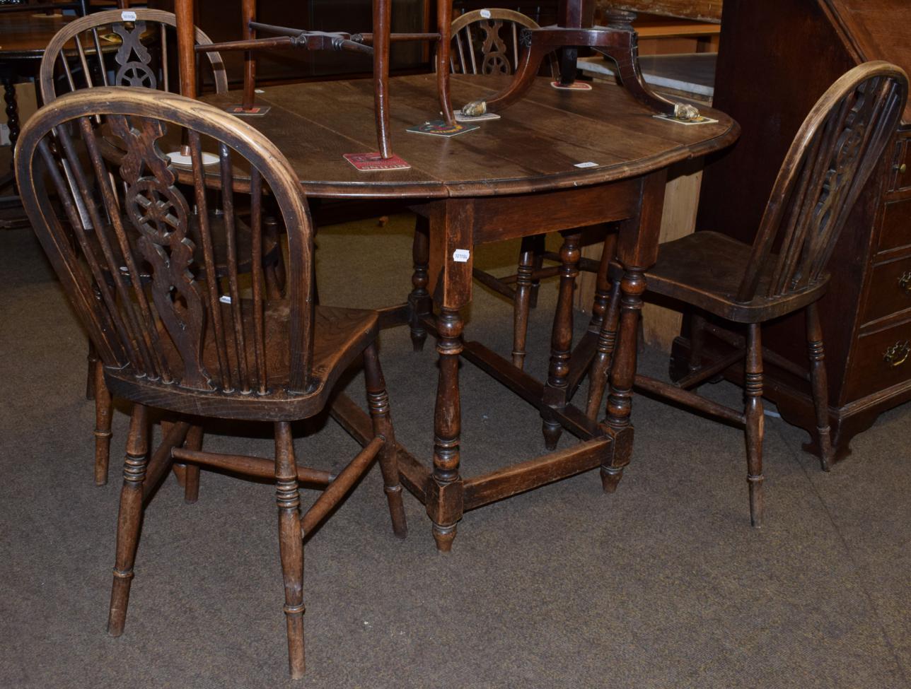 Lot 1227 - An oak gateleg table on baluster turned legs; together with a set of four wheel back chairs (5)