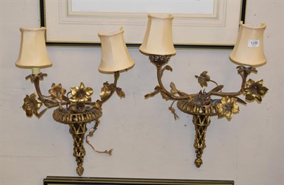 Lot 1256 - A pair of gilt metal three light wall sconces in the form of pierced urns issuing floral branches