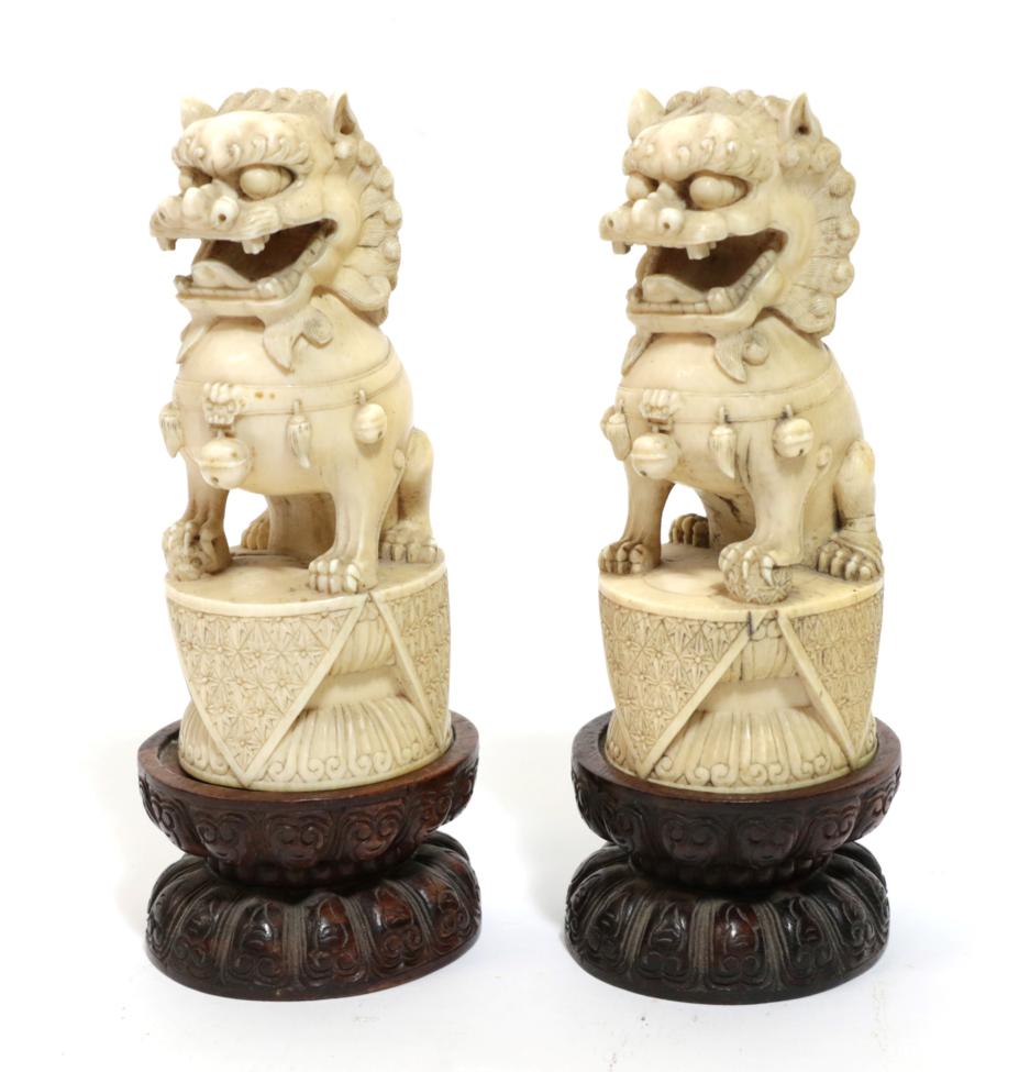 Lot 71 - A Pair of Chinese Carved Ivory Dogs of Fo, 19th century, of traditional form, sitting on oval...