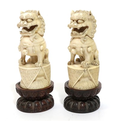 Lot 71 - A Pair of Chinese Carved Ivory Dogs of Fo, 19th century, of traditional form, sitting on oval...