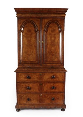 Lot 319 - A Figured Walnut and Featherbanded Bookcase Cabinet, the cavetto cornice above a cushion shaped...