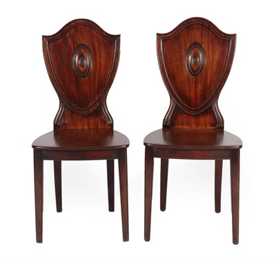 Lot 336 - A Pair of George III Mahogany Hall Chairs, circa 1800, the moulded shield back supports above solid