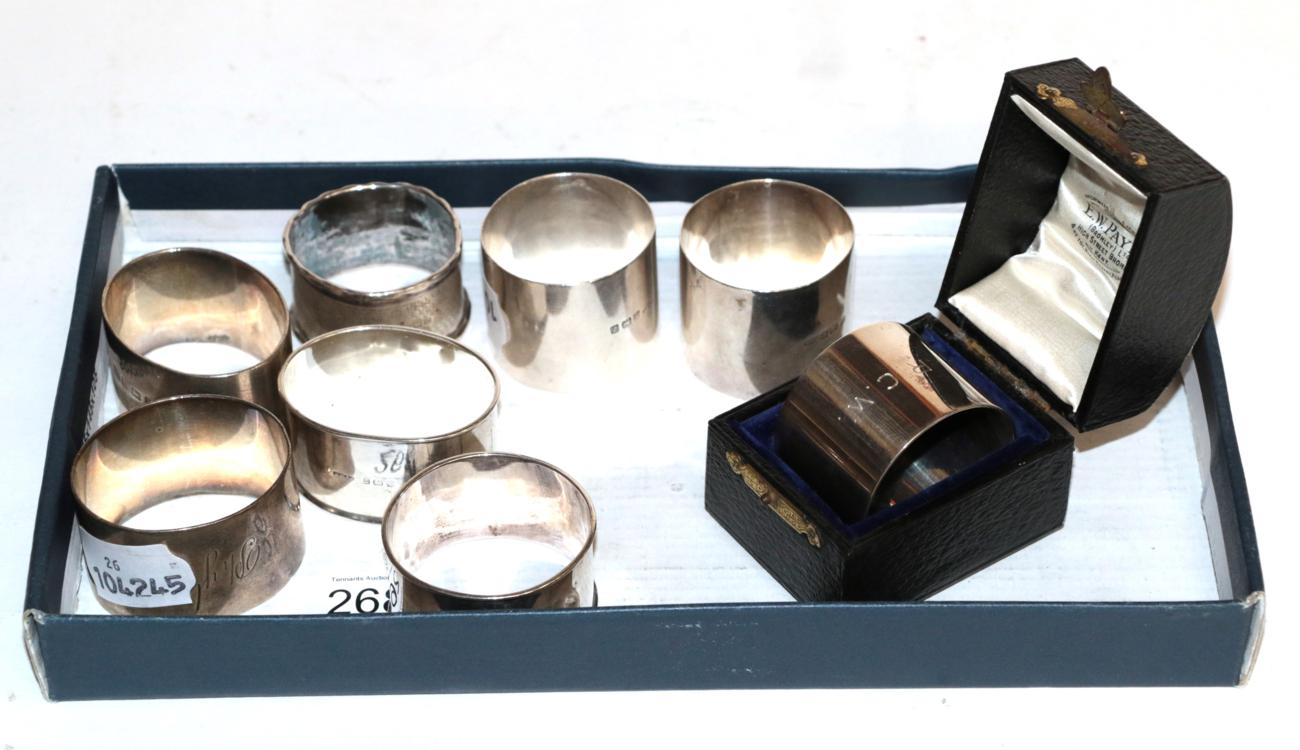 Lot 268 - A collection of eight various silver napkin-rings, including one cased, some variously...
