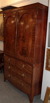 Lot 1200 - A mahogany linen press circa 1820/30, with two arched cupboard doors enclosing hanging space,...