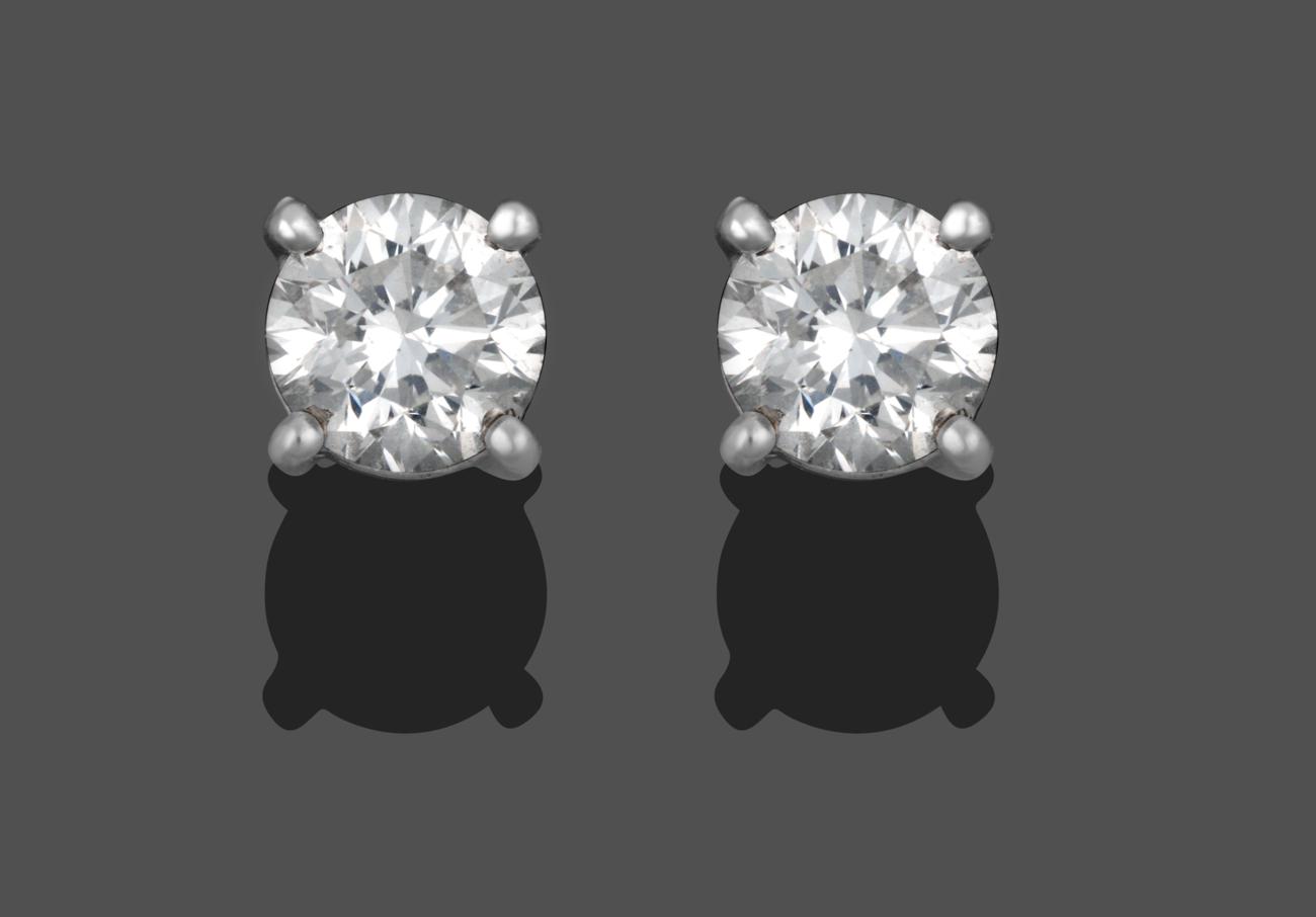 Lot 1009 - A Pair of Diamond Solitaire Stud Earrings, the round brilliant cut diamonds in white four claw...