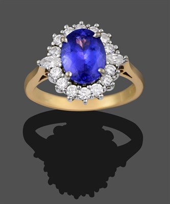 Lot 1026 - An 18 Carat Gold Tanzanite and Diamond Cluster Ring, the oval cut tanzanite within a border of...