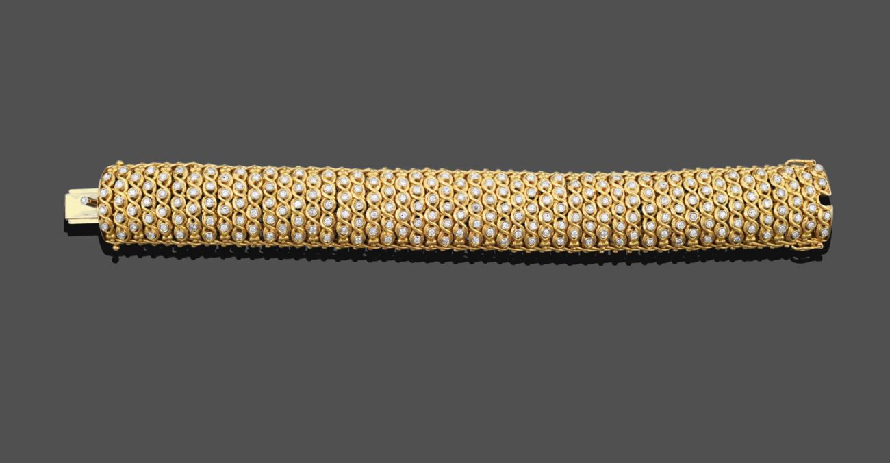 Lot 1039 - A Diamond Bracelet, the yellow broad fancy link bracelet set throughout with alternating columns of