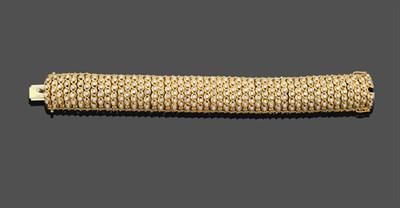 Lot 1039 - A Diamond Bracelet, the yellow broad fancy link bracelet set throughout with alternating columns of