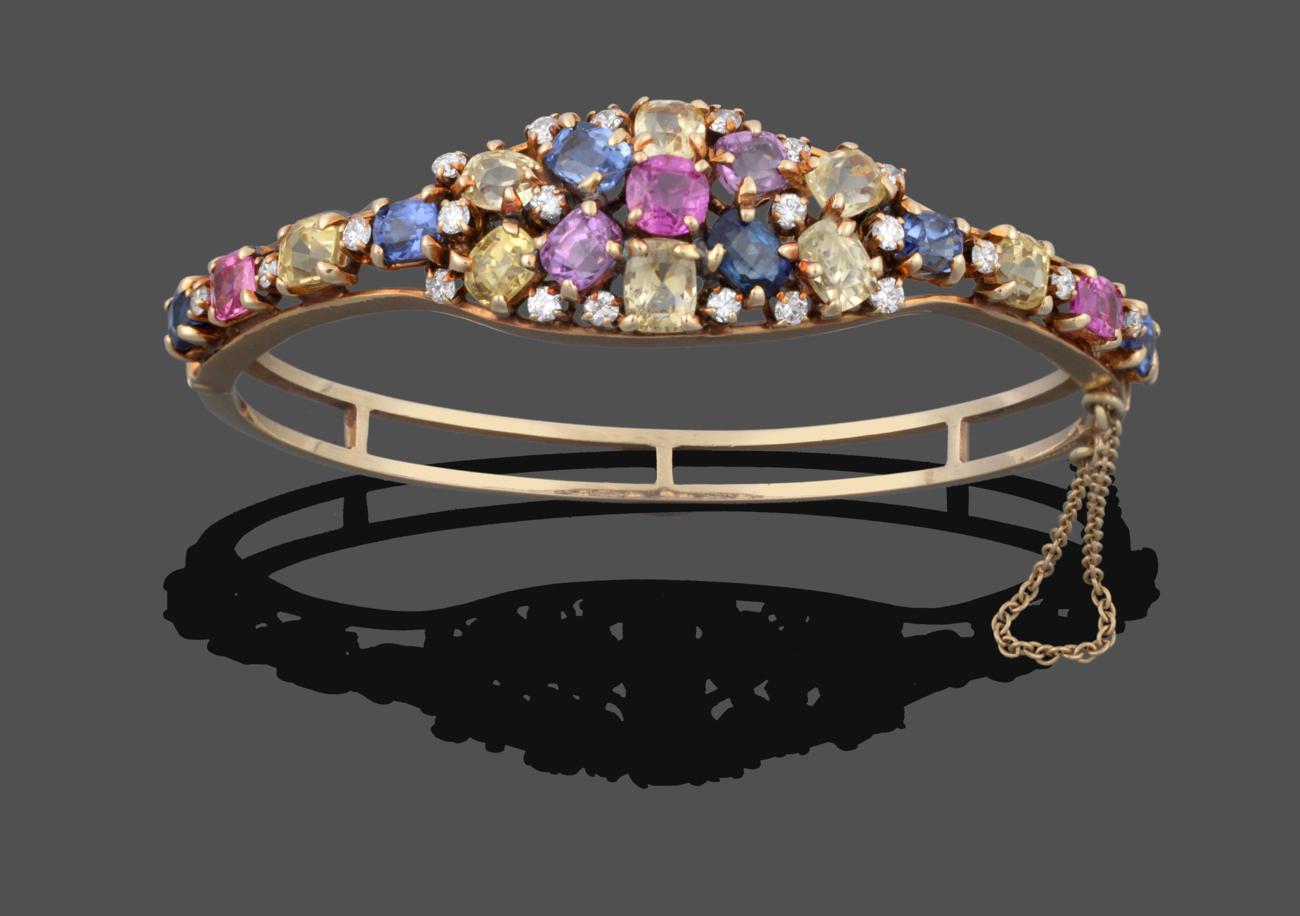 Lot 1041 - A Multi-Gemstone Cluster Bangle, the cluster set throughout with vari-shaped pink, blue, yellow and
