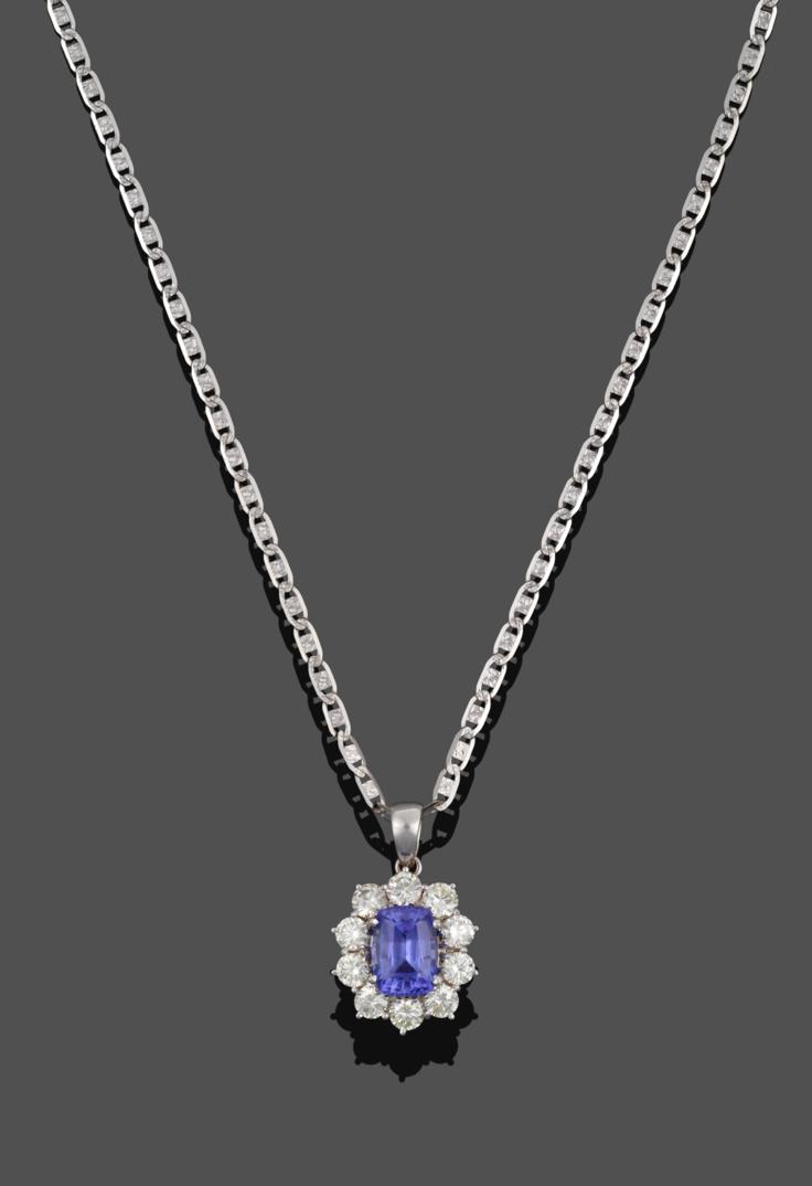 Lot 1044 - An 18 Carat White Gold Tanzanite and Diamond Cluster Pendant on Chain, the cushion cut...